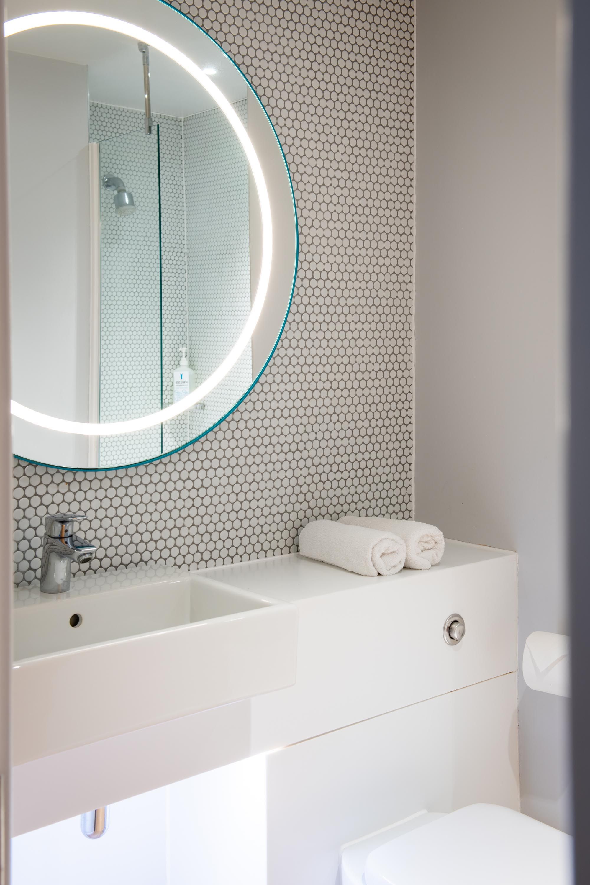White bathroom with sink and light up mirror on wall