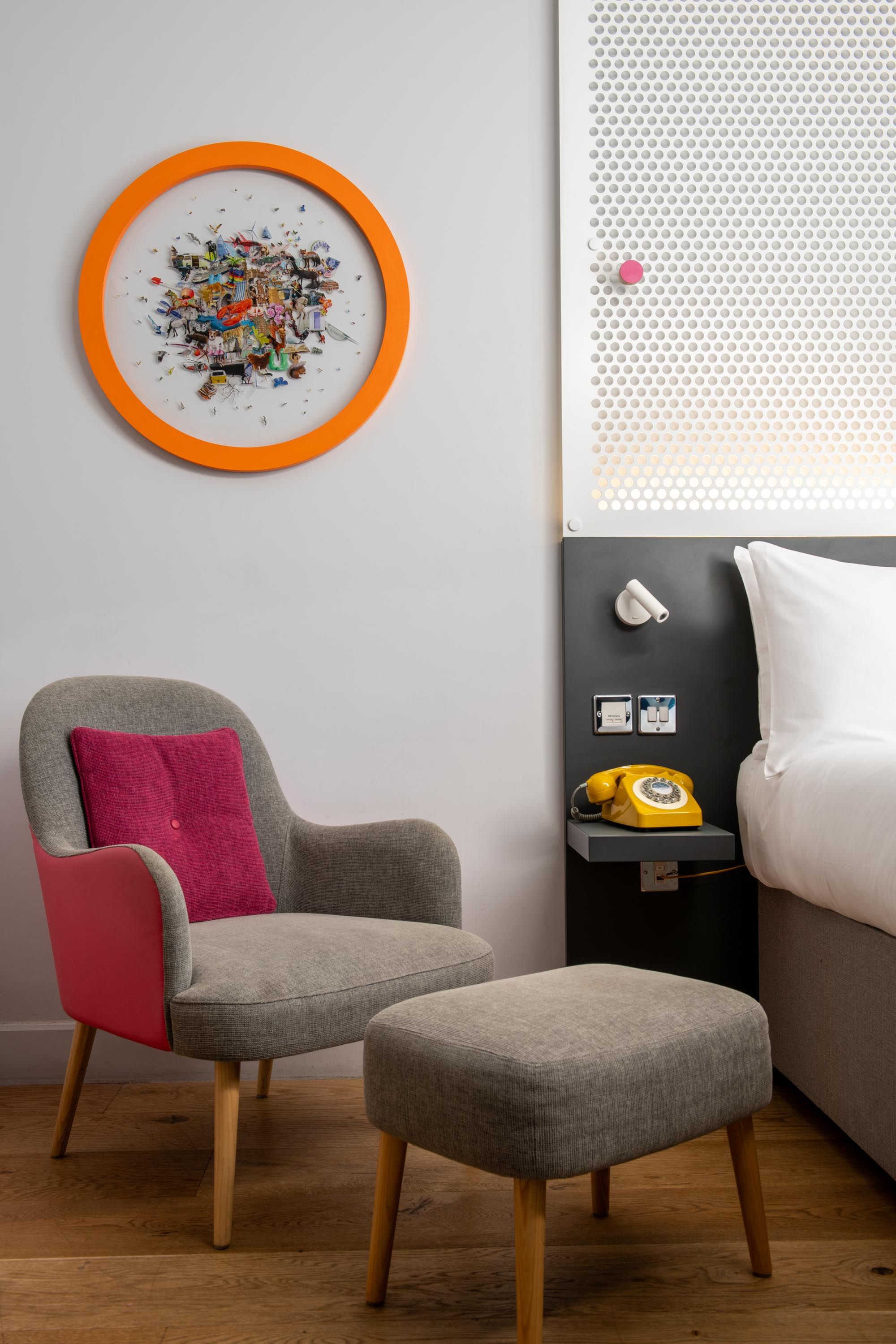 Chair with pink cushion next to bed with matching foot stool