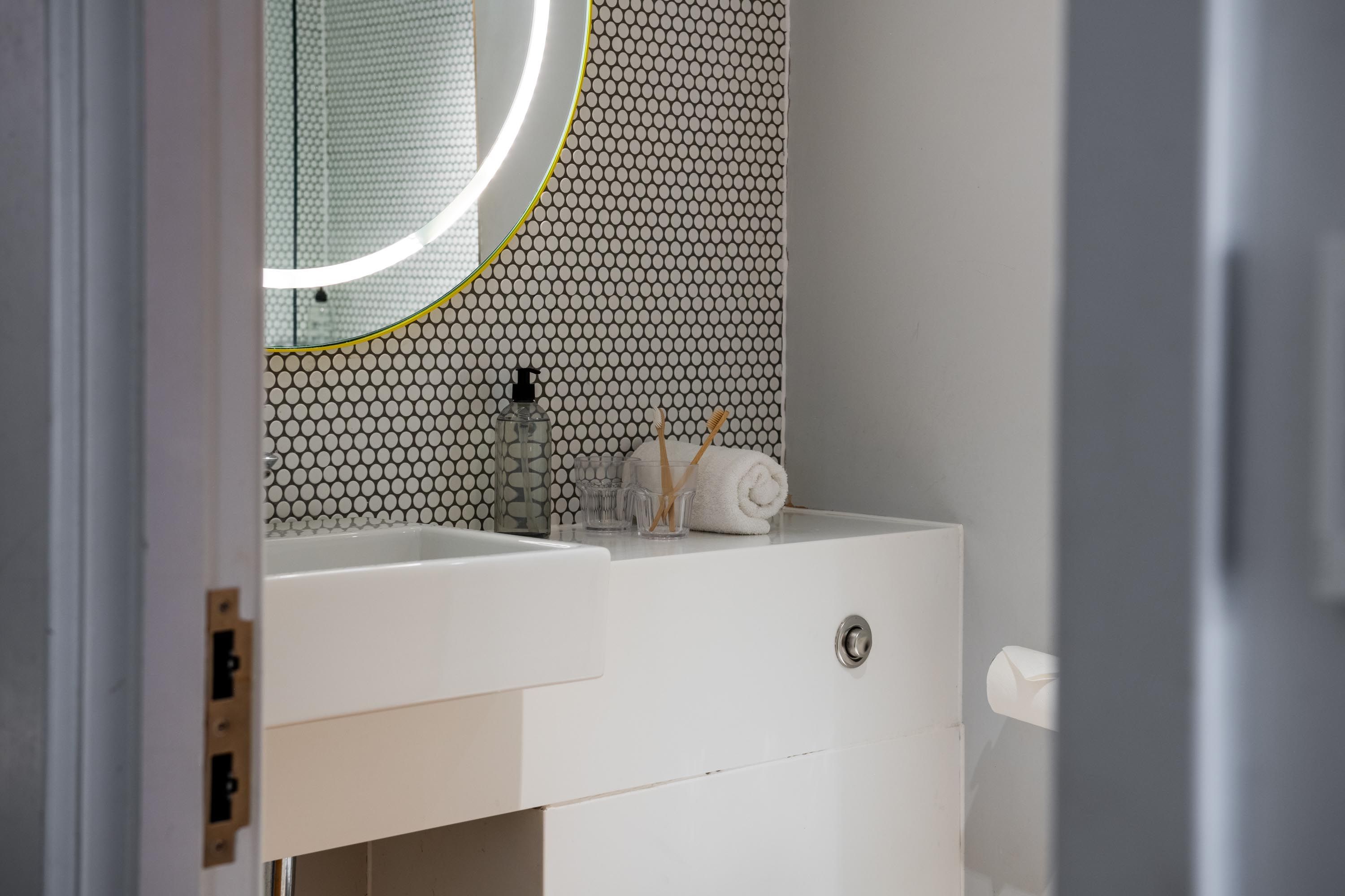 Modern white bathroom with sink and light wall mirror