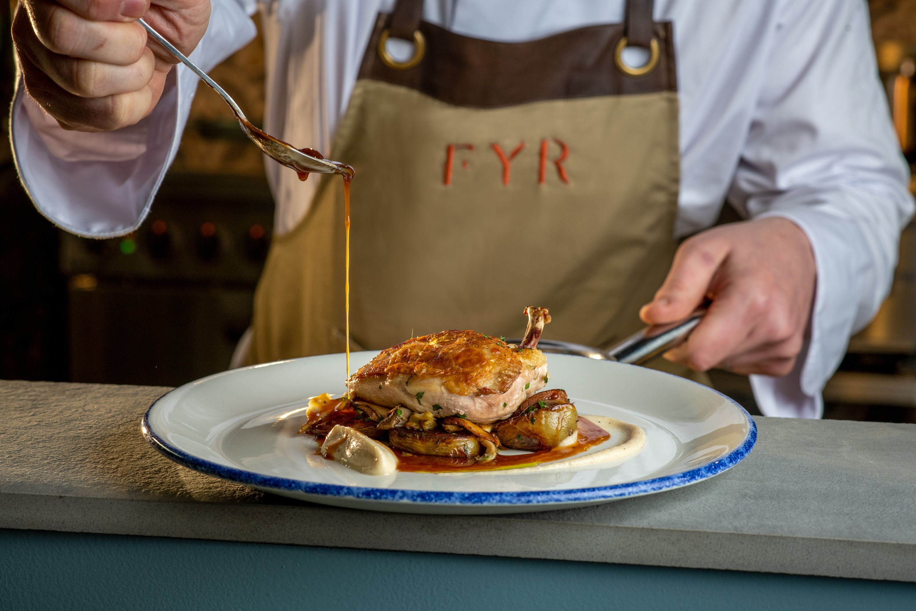 Chef putting gravy on Chicken dish