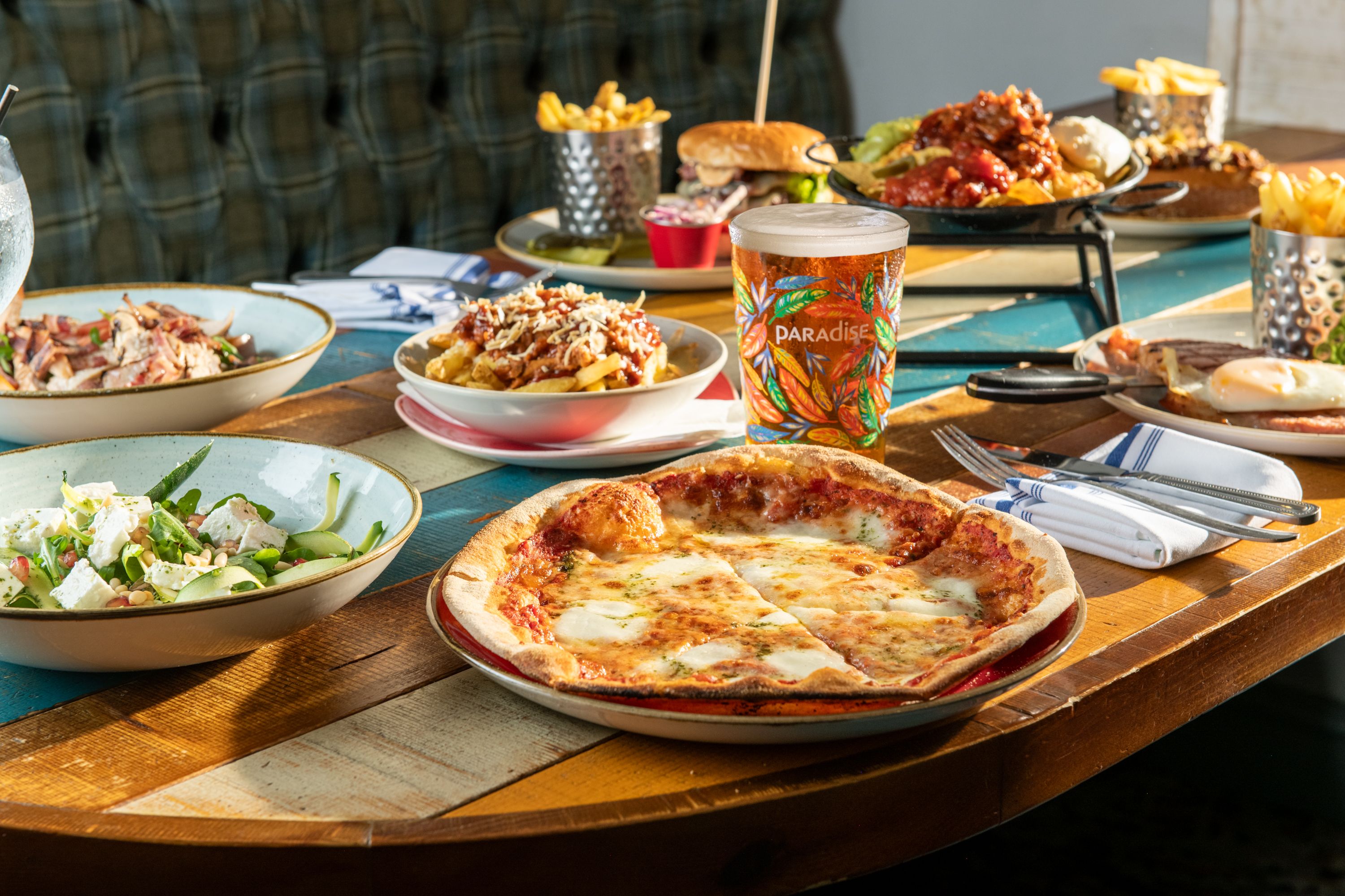 Margherita pizza with a pint of paradise on table with other dishes